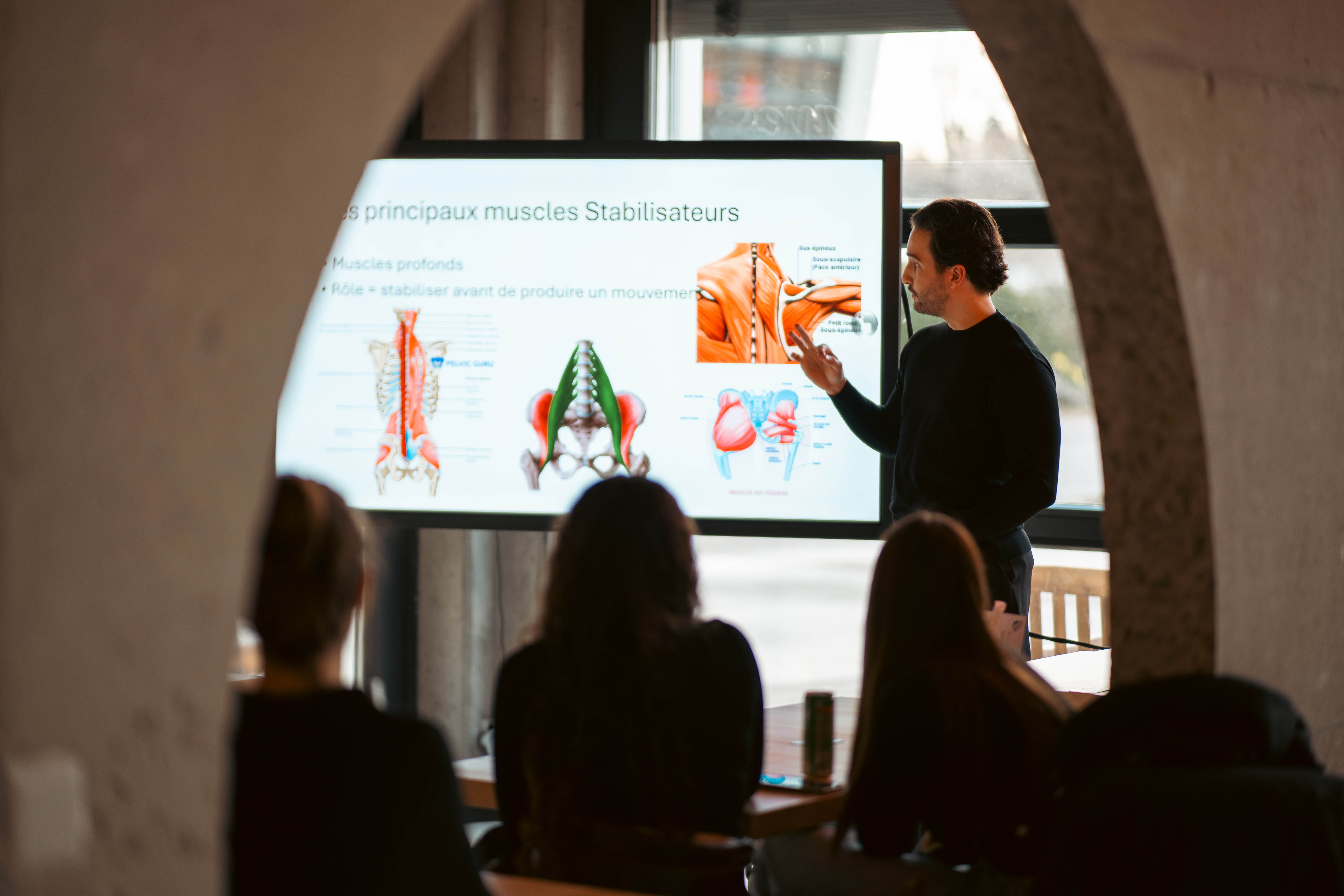 Conférencier présentant l'anatomie musculaire lors d'une soirée L'Essentiel